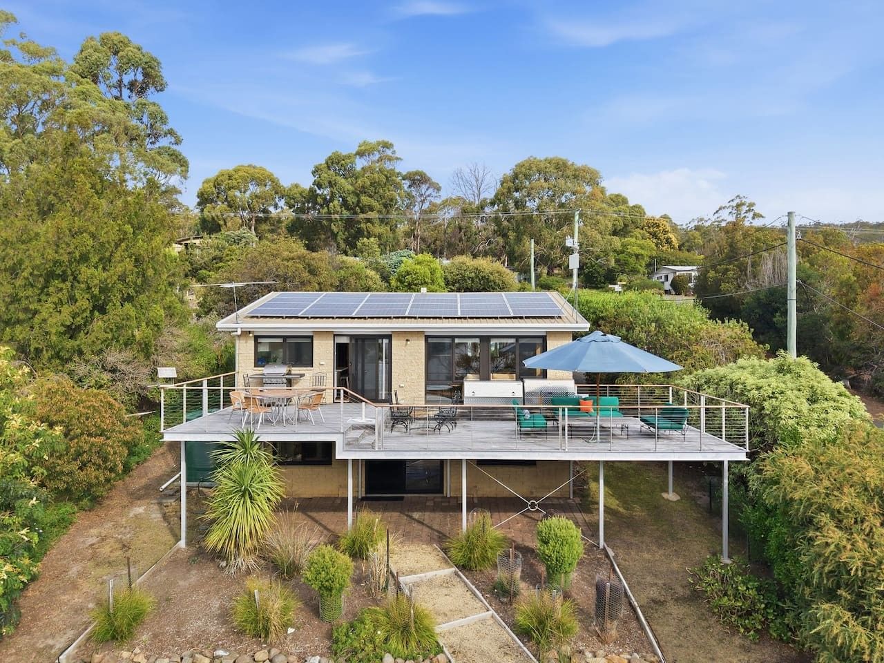 Una casa moderna con terraza, paneles solares y jardín.