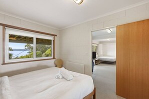 Un dormitorio con cama, ventana con vistas, puerta de madera y baño visible.