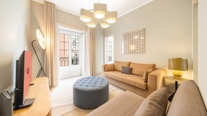 En moderne stue med sofa, skammel og lampe.