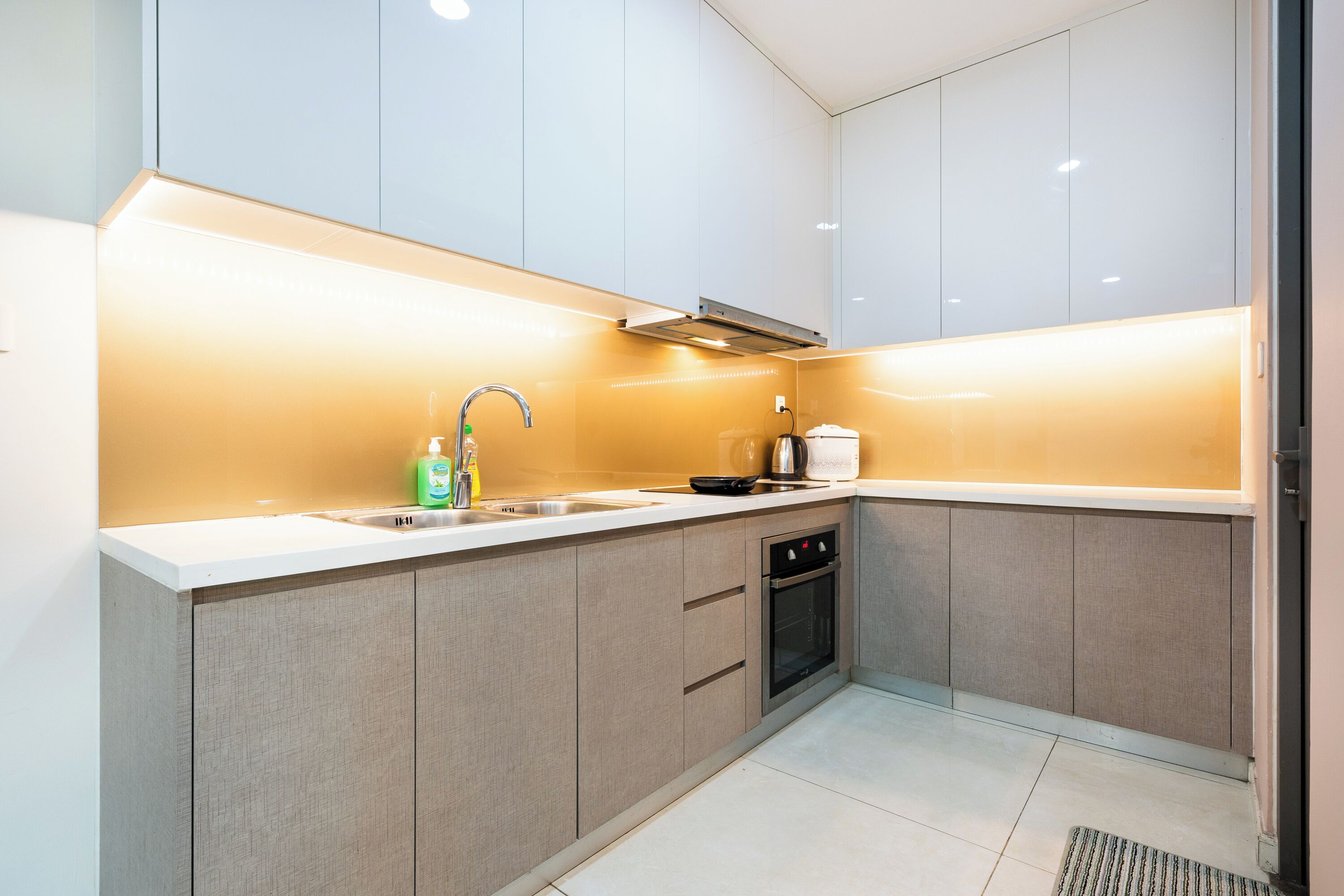 A modern kitchen with white cabinets, a stainless steel sink, and a built-in oven.