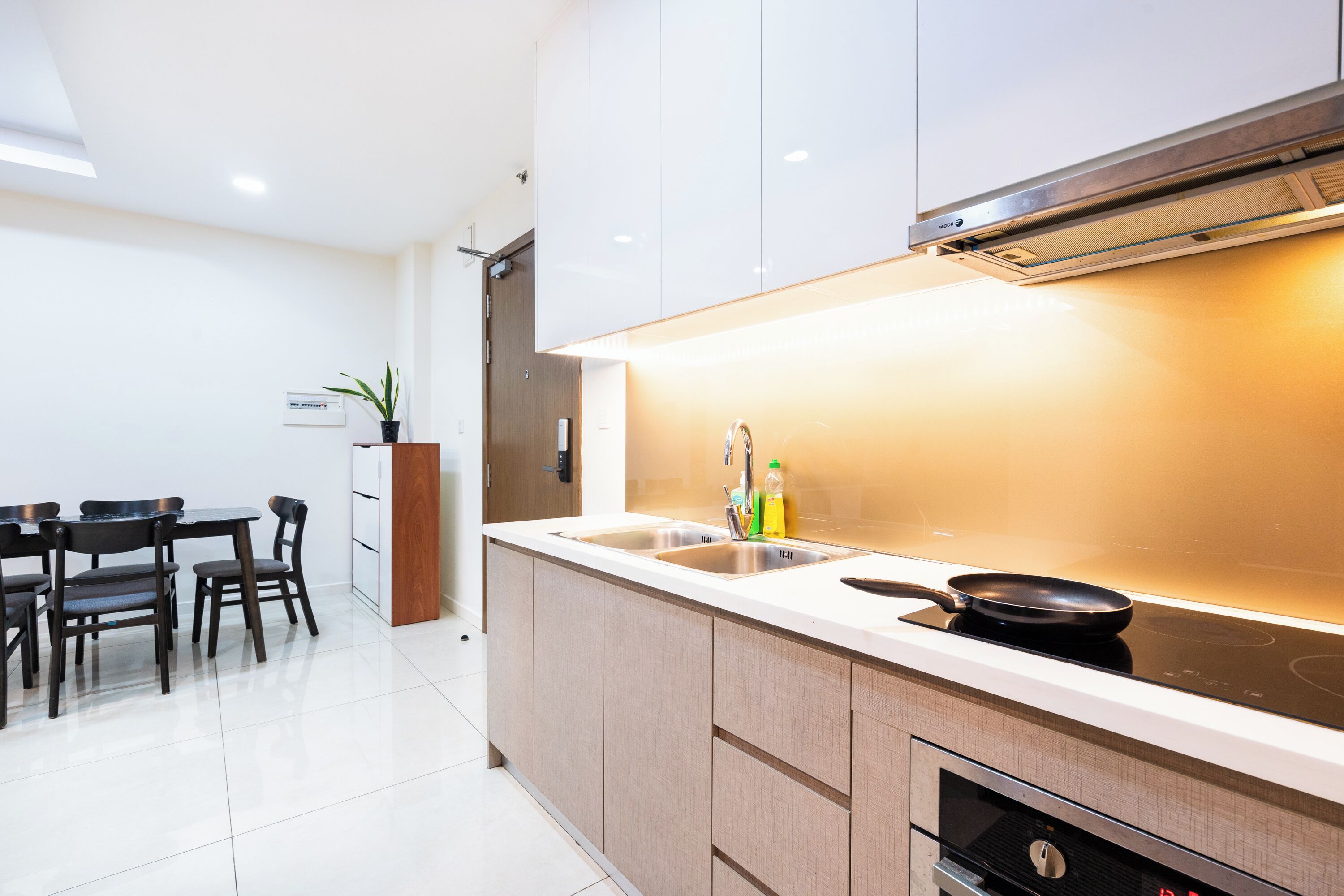 Una cocina moderna con estufa integrada, un fregadero y un comedor con sillas.