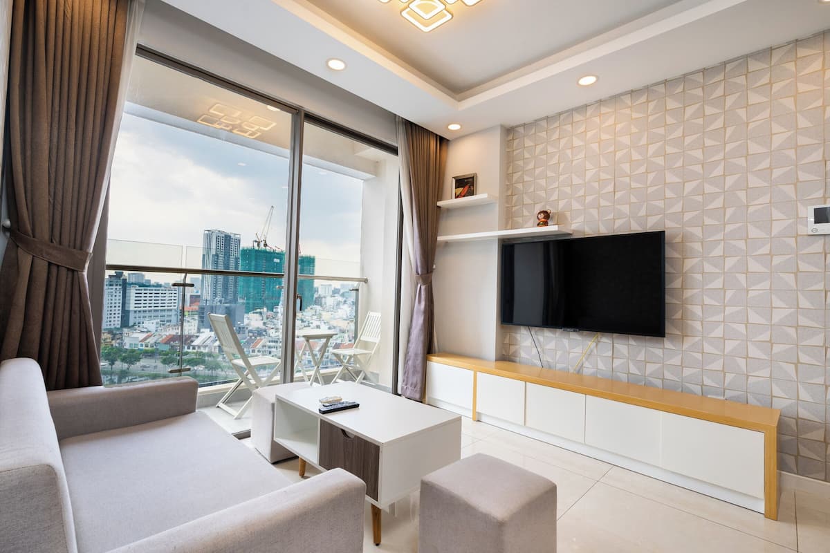 A modern living room with a large window, a flat-screen TV, and a city view.