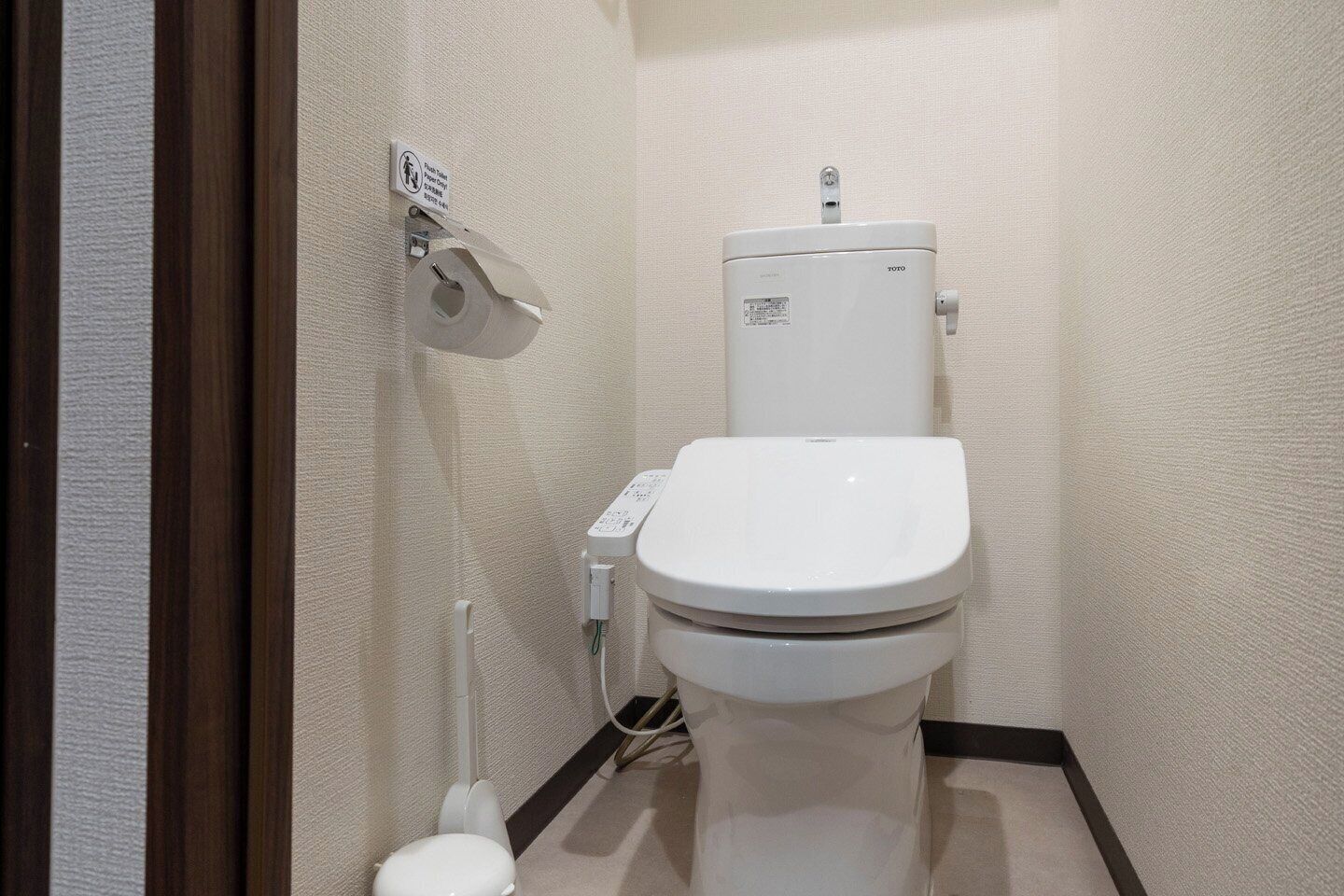 Une petite salle de bain propre, équipée de toilettes, d’un distributeur d’essuie-tout et d’un sèche-mains.