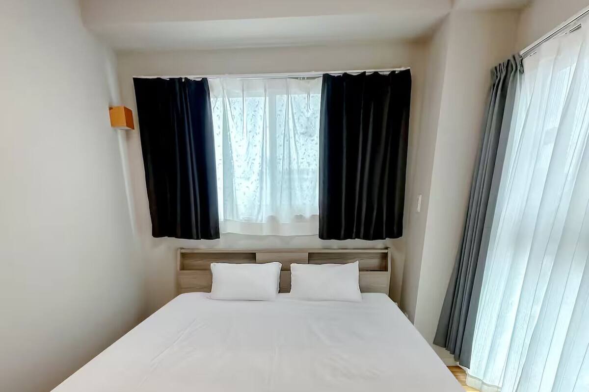 A hotel room with a large bed, a window with curtains, and a wooden headboard.