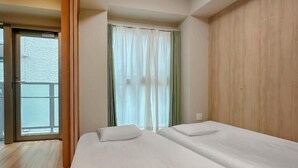 Een hotelkamer met een groot bed, een raam met gordijnen en een houten wand.