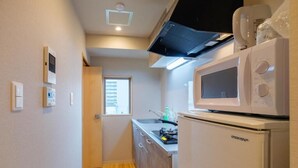 Een kleine keuken met een magnetron, een koelkast en een fornuis.