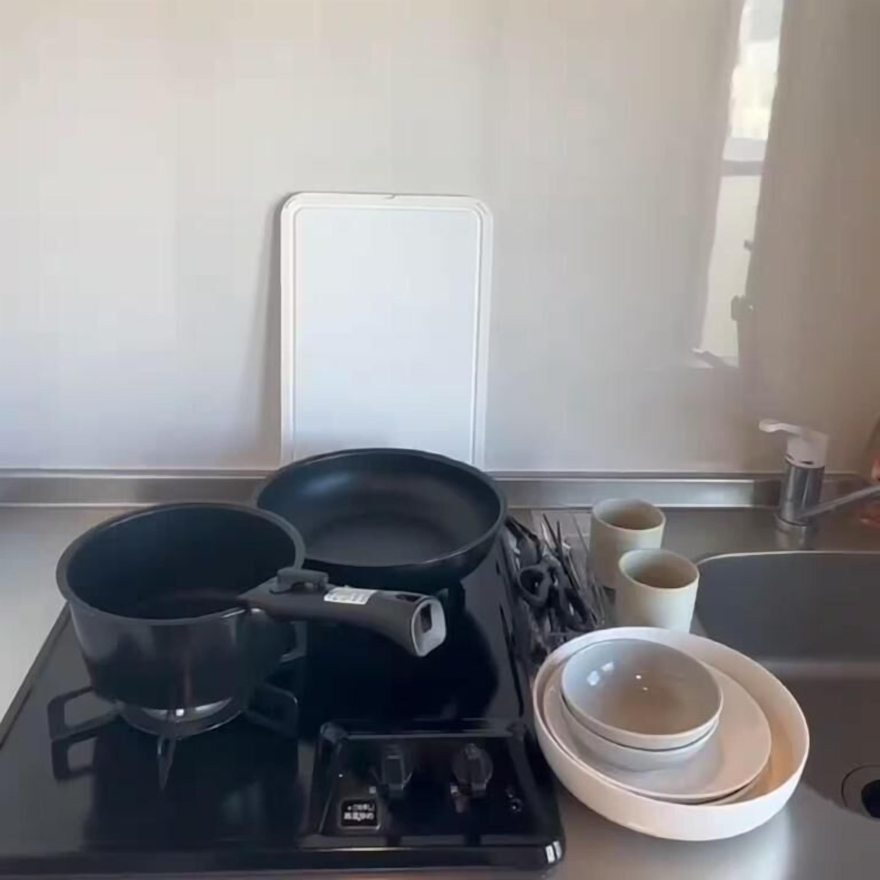 Une cuisine équipée d’une cuisinière, de casseroles, d’une bouilloire et d’un évier.