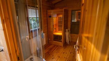 A wooden cabin interior with a glass door, a small window, and a wooden floor.