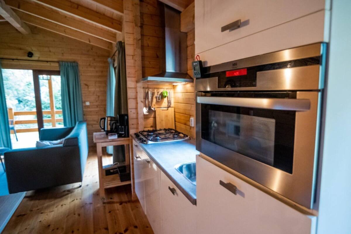 Una cocina compacta con estufa a gas, horno y cafetera sobre una mesita.