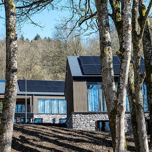 A modern building with solar panels, stone walls, and large windows.