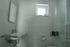 A bathroom with a white sink, mirror, and a small window. - Family Comfort in Guntersberge (Harzgerode)