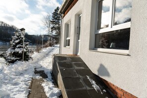 A snow-covered pathway leading to a building with large windows and a brick foundation.