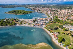 An aerial view of a coastal town with a marina, beach, and residential area. - Apartment Near Pula With Sea View Balcony (Medulin)