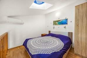 A bedroom with a bed, a ceiling fan, a wall-mounted air conditioner, a painting, and a wooden wardrobe. - Apartment Near Pula With Sea View Balcony (Medulin)