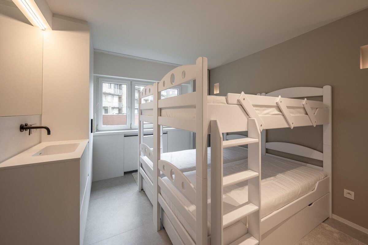 A bunk bed room with a window, a sink, and a mirror.