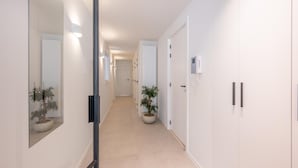 A hallway with a mirrored wall, a potted plant, and a door with a phone on the wall. - Modern Seaside Escape (Knokke-Heist)