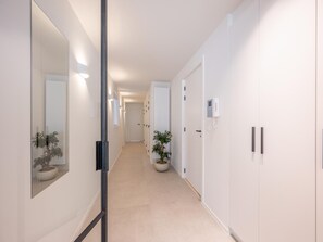 A hallway with a mirrored wall, a potted plant, and a door with a phone on the wall. - Modern Seaside Escape (Knokke-Heist)