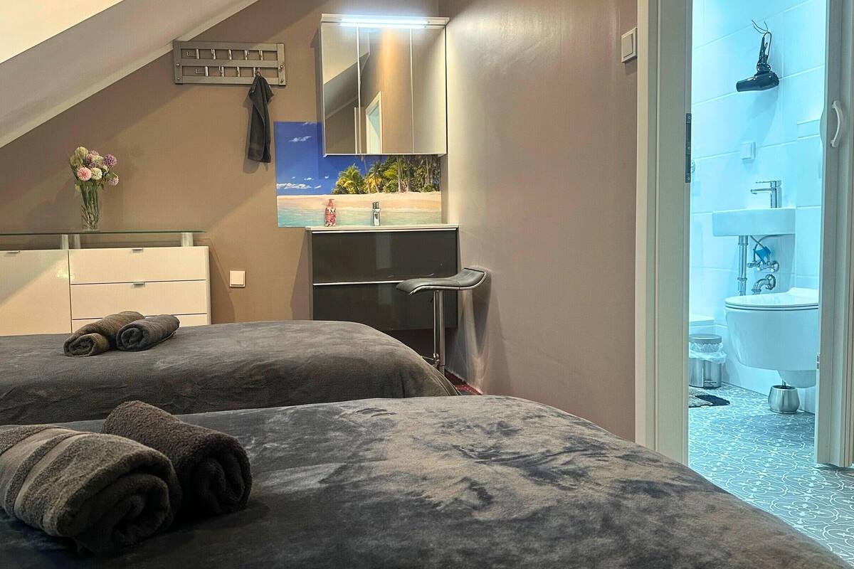 Ein Hotelzimmer mit zwei Betten, einem Badezimmer, einem Spiegel und einem kleinen Schreibtisch.