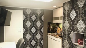Una cocina moderna con un papel tapiz estampado en blanco y negro, un lavamanos empotrado y un armario blanco.