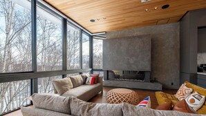 A modern living room with a large sofa, a round ottoman, and a fireplace. - Yuzen (Kutchan)