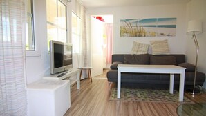 A living room with a television, sofa, coffee table, and a lamp. - Ferienhaus mit Kamin am Achterwasser in Lutow (Luetow)