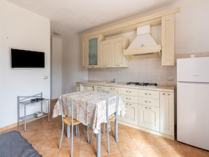A compact kitchen with a dining table, chairs, a stove, and a refrigerator. - In the Residence, Terrace and air Conditioning (Castelsardo)