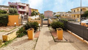 Rua residencial com casas, um calçadão pavimentado e um carro estacionado na lateral.