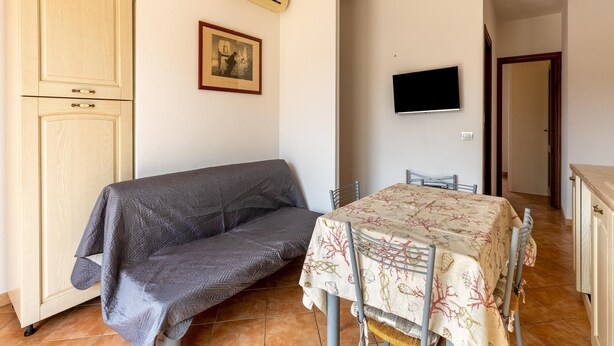 Um quarto com sofá, mesa de jantar com cadeiras, TV de tela plana e um quadro na parede.
