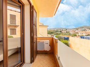 A balcony with a view of a residential area, a sliding glass door, and an air conditioning unit. - In the Residence, Terrace and air Conditioning (Castelsardo)