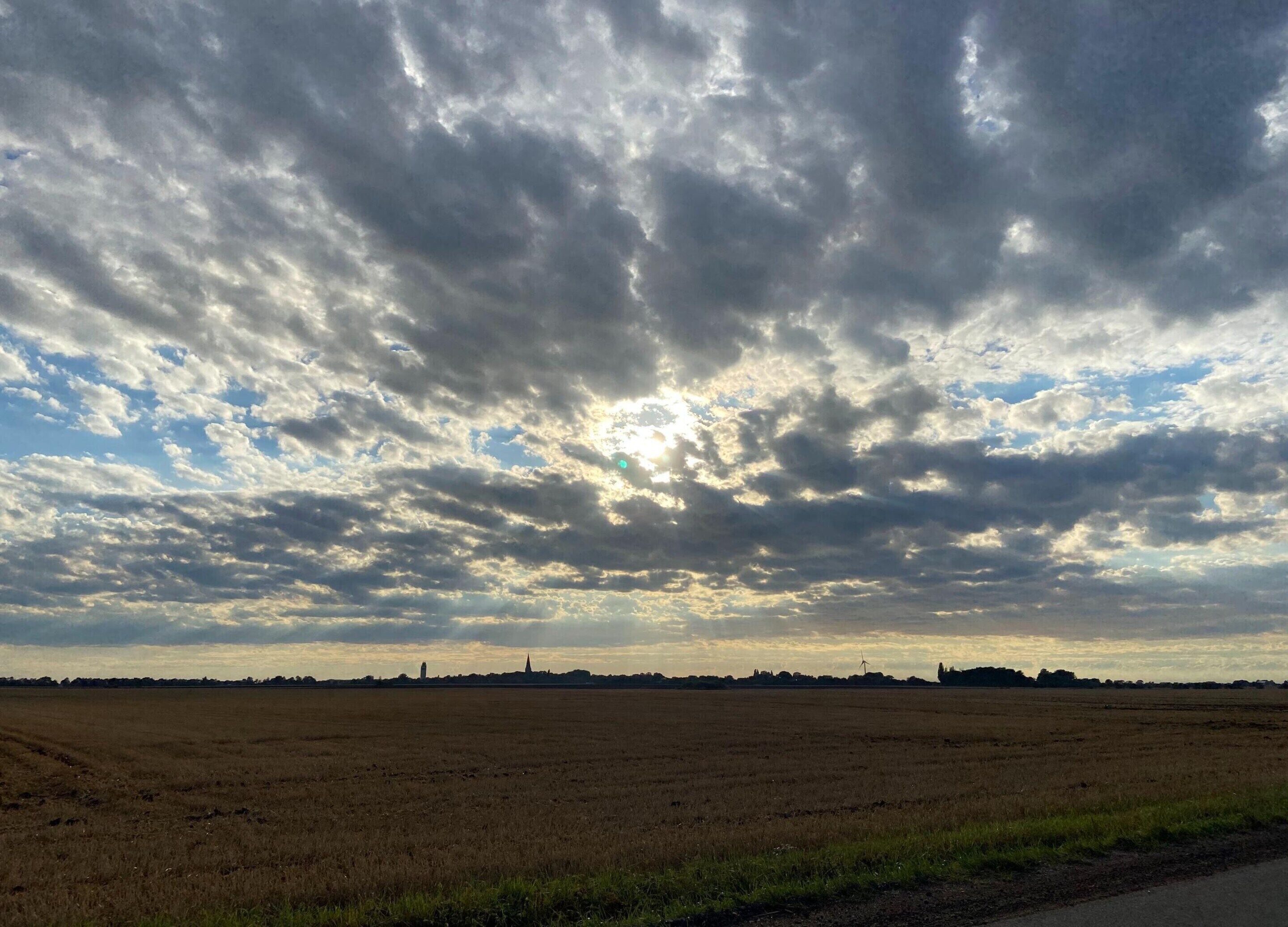 A wide, flat landscape with a cloudy sky and a distant horizon line.