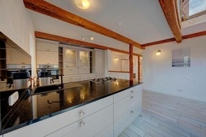 A modern kitchen with a black countertop, white cabinetry, and wooden beams on the ceiling.