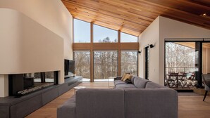 A modern living room with a sectional sofa, a flat-screen TV, and a fireplace. - Shion (Kutchan)
