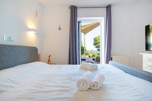 Ein Hotelzimmer mit Bett, Blick ins Freie, einem Vorhangfenster, einem Heizkörper und einem Wandfernseher.