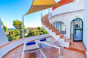 Eine Terrasse mit Liegestühlen, einer Treppe und Blick aufs Meer.