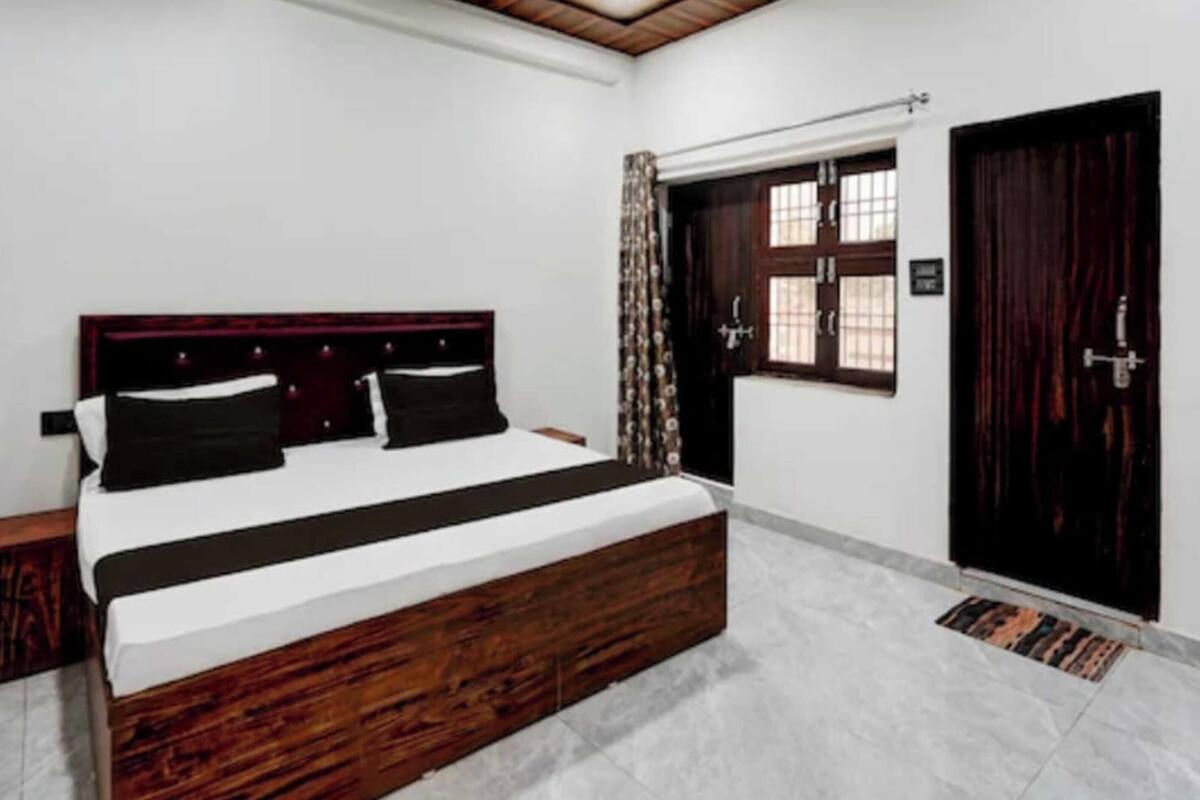Un dormitorio con cama de madera, una ventana con cortinas y una puerta oscura.