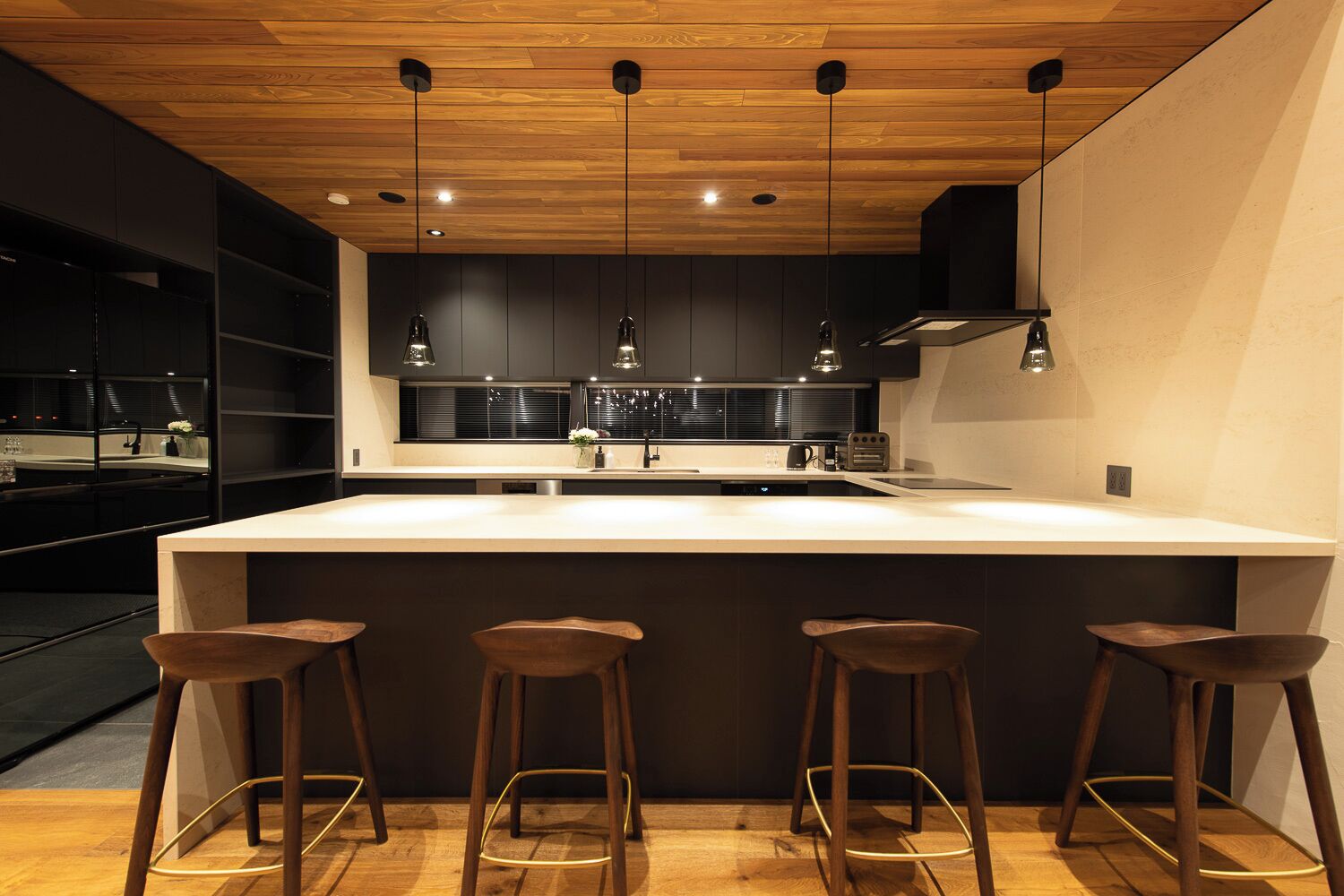 Una cucina moderna con un'isola grande, mobili scuri e illuminazione a sospensione.