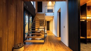 Een modern interieur met een houten trap, een schoenenrek en een mand.