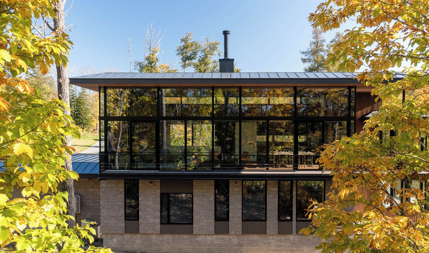 A modern building with large windows, a flat roof, and a chimney.