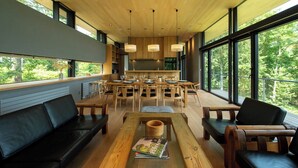 A modern interior with a dining area, seating, and large windows. - Hiyoku (Niseko)