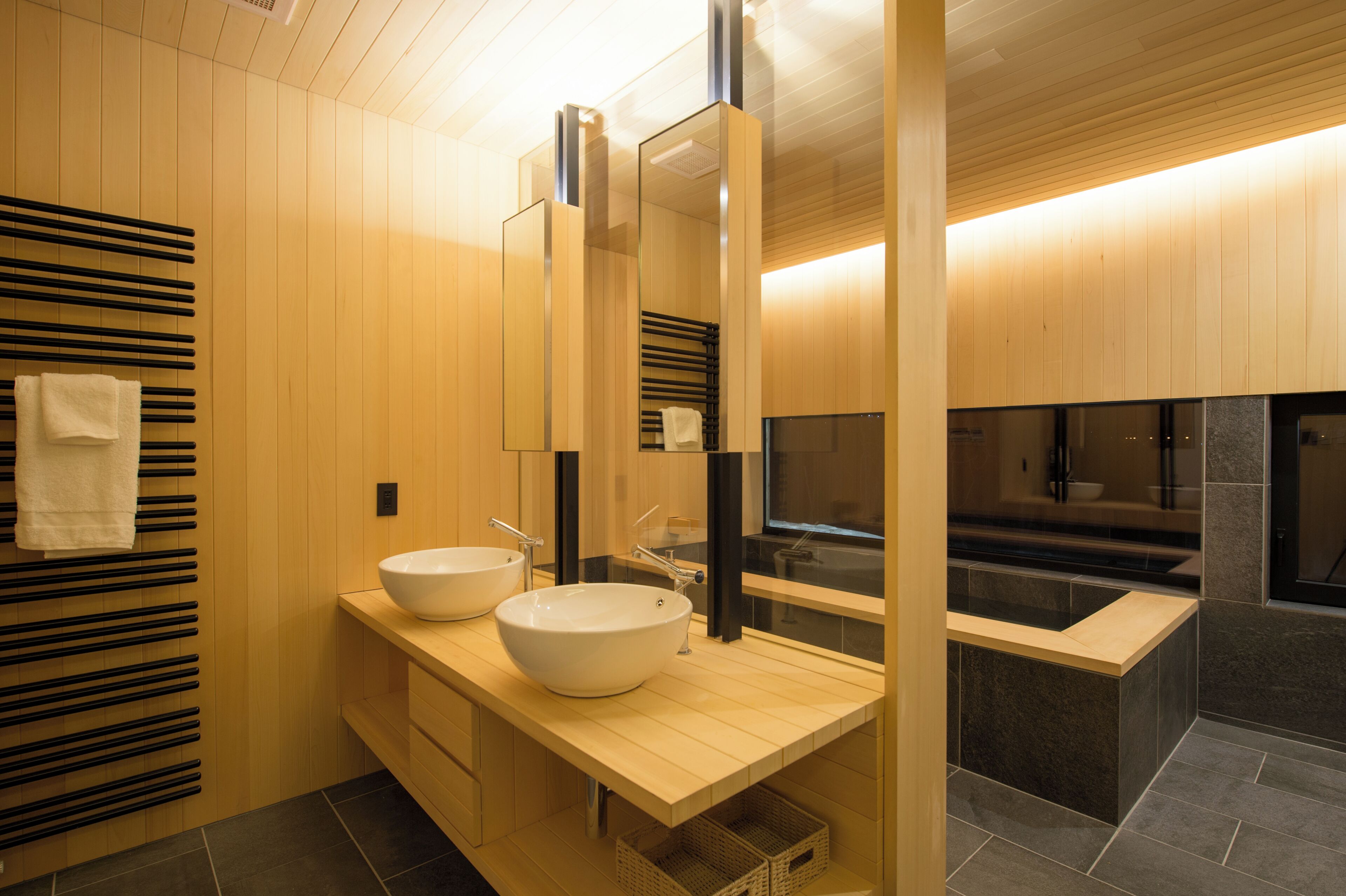 A modern bathroom with two sinks, a large mirror, and wooden paneling.