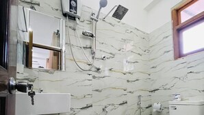 A bathroom with a marble wall, a white sink, a toilet, and a shower. - Ella Hillcrest Heaven (Ella)