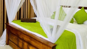 A bed with a wooden headboard, green bedding, and white mosquito netting. - Ella Hillcrest Heaven (Ella)