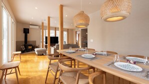 Un'area pranzo con un lungo tavolo di legno apparecchiato per quattro persone, circondato da sedie di legno.