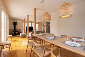 A dining area with a long wooden table set for four, surrounded by wooden chairs. - Yukimine (Kutchan)