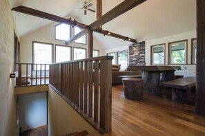 Un loft spacieux avec un escalier en bois, une cheminée en pierre et de grandes fenêtres.