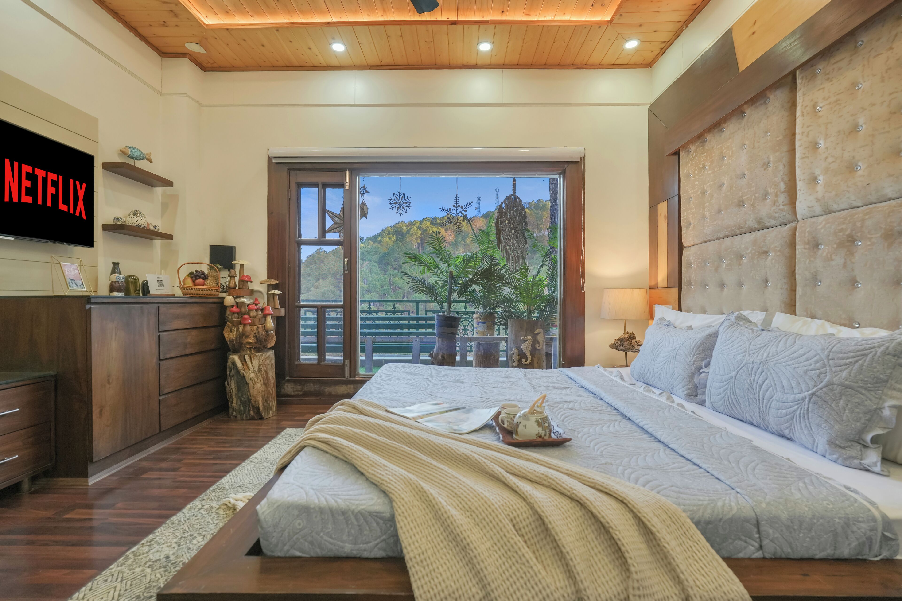 A bedroom with a bed, a TV, a desk, and a view of a balcony.