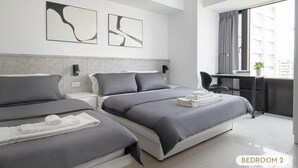 Una camera da letto moderna con due letti, una scrivania e una finestra con tende.