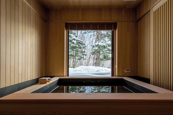 Un intérieur en bois avec une grande fenêtre, un banc en bois et une petite boîte en bois.