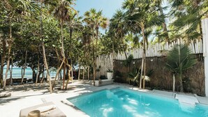 Ein Pool, umgeben von Palmen und einem weißen Zaun.