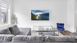 Un salon moderne avec un canapé, une table basse et un fauteuil bleu.